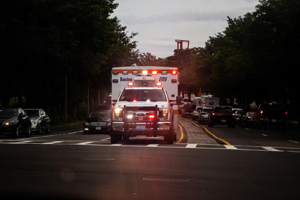 Front of an ambulance as it drives with lights and sirens down the street. 