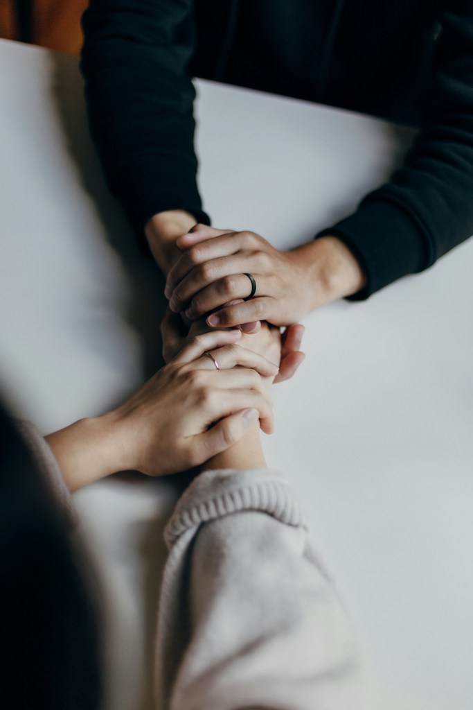 Two people holdings hands on top of a white counter. 