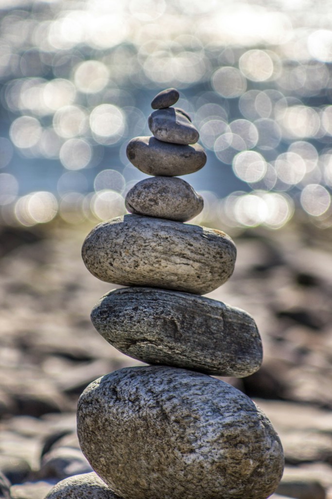 Stacked stones on a beach with water in the background.