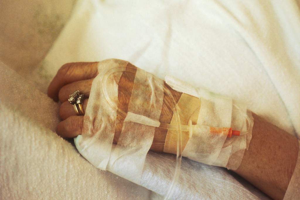 A patient's left hand with an IV in the forearm.
