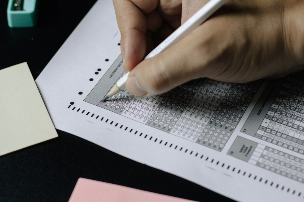 A student taking a multiple choice exam on a scantron with a pencil.