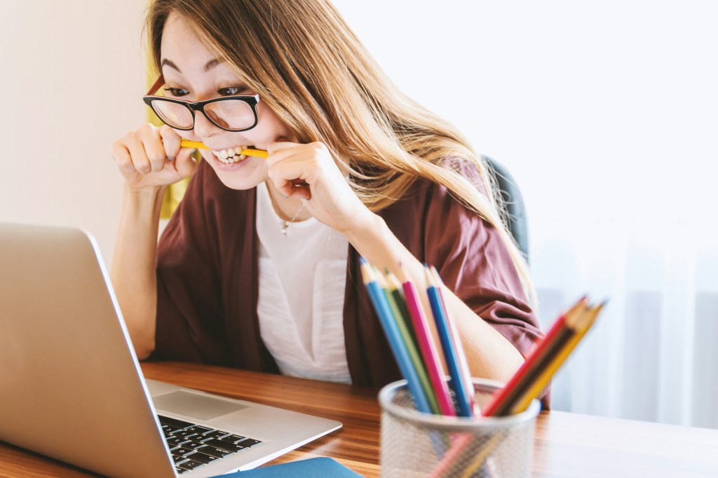 Nervous female paramedic studying for her National Registry exam while biting a pencil. 