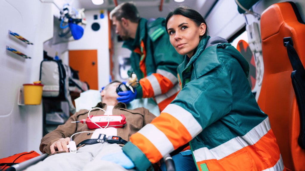 Two paramedics working on a patient while one of them looks off into the distance. 