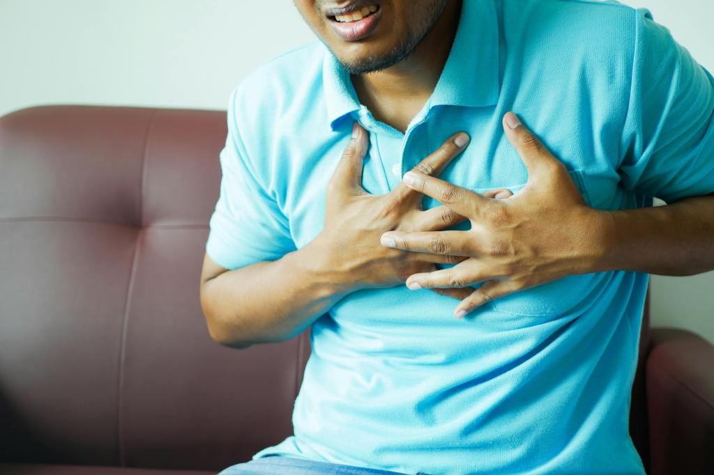A man complaining of chest pain and grasping his chest. 